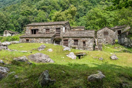Casas de piedra en ruinas y molinos en un pueblo de montaña abandonado en los Alpes