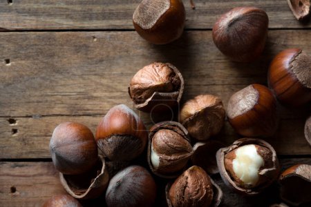 Photo for Cracked and unbroken shelled hazelnuts on a wooden background. - Royalty Free Image