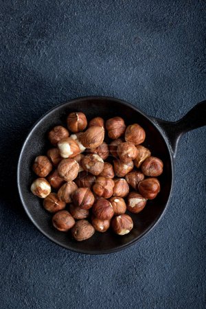 Photo for Raw hazelnuts in a bowl on a black background. Nuts in a bowl on a dark background. - Royalty Free Image