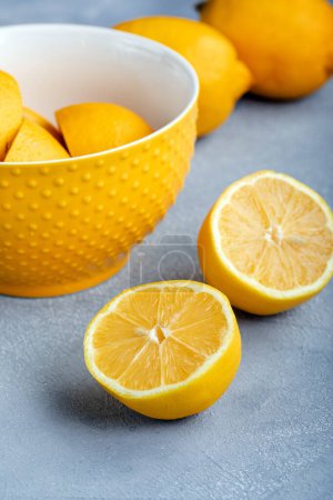 Téléchargez les photos : Un tas de citrons sur fond gris. Citrons frais dans un bol ; entiers et coupés en deux. - en image libre de droit