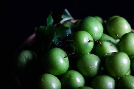 Téléchargez les photos : Gros plan de prunes vertes fraîches dans un bol sur fond sombre. Fruits à prunes verts. - en image libre de droit