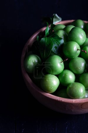 Téléchargez les photos : Prunes vertes fraîches dans un bol sur fond sombre. - en image libre de droit