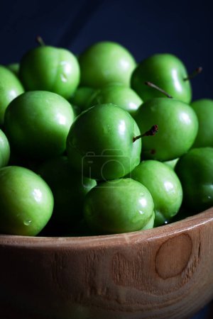 Téléchargez les photos : Prunes vertes fraîches dans un bol sur fond sombre. - en image libre de droit