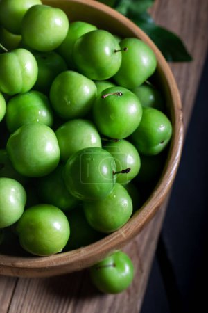 Téléchargez les photos : Prunes vertes fraîches dans un bol sur fond en bois. Gros plan. Vue grand angle. - en image libre de droit