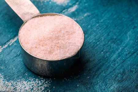 Photo for Pink Himalayan salt in measuring spoon on blue wooden background. Selective focus. Toned. - Royalty Free Image
