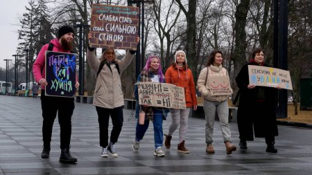 Téléchargez les photos : Kharkiv, Ukraine - mars, 08, 2023 : Les filles et un gars marchent sur la place de la ville avec des affiches contre le sexisme, contre le patriarcat, avec des inscriptions Juste seins ne sont pas une invitation au sexe, Pas de sexisme - en image libre de droit