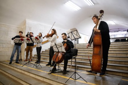 Téléchargez les photos : Kharkiv, Ukraine - 25 avril 2022 : Les jeunes musiciens donnent un concert de musique classique dans un tunnel du métro. Les musiciens jouent du violoncelle et des violons - en image libre de droit
