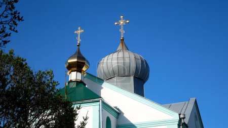 Téléchargez les photos : Une église orthodoxe avec des dômes dorés et gris et des croix dorées brillantes sur eux contre le ciel bleu. Orthodoxie. Église du Patriarcat de Moscou en Ukraine. Vacances orthodoxes - en image libre de droit