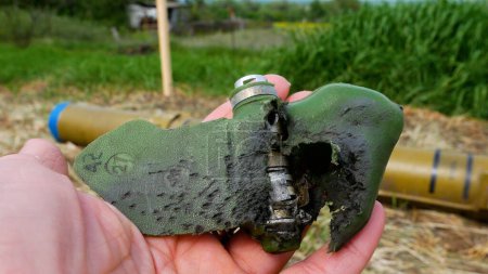 Eine zerrissene Antipersonenmine, die durch eine Explosion beschädigt wurde, ein Blütenblatt in seiner Hand. Entminung des Territoriums. Russisch-ukrainischer Krieg 2022-2023