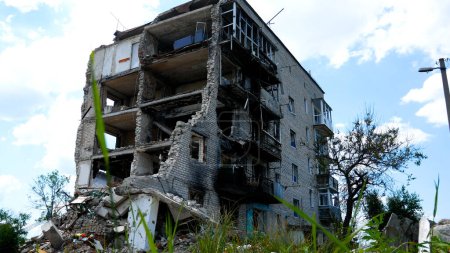 Foto de Un edificio residencial de varios pisos destruido por un ataque aéreo en una ciudad ucraniana. La entrada de la casa fue destruida, una palanca sin paredes, rastros de fuego en las paredes. Guerra ruso-ucraniana - Imagen libre de derechos