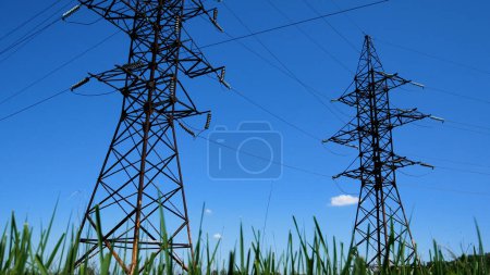 Foto de Torres de líneas eléctricas de alto voltaje contra el cielo azul. Producción y transporte de energía eléctrica para los consumidores. Infraestructuras energéticas - Imagen libre de derechos