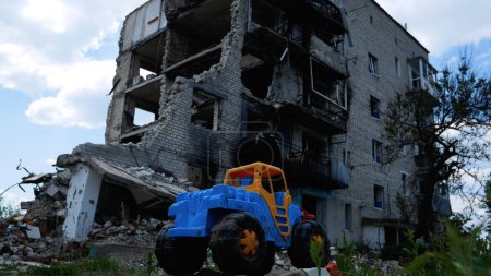 A childrens toy against the background of a multi-storey residential building destroyed by an air strike in a Ukrainian city. Russian-Ukrainian War 2022-2023.