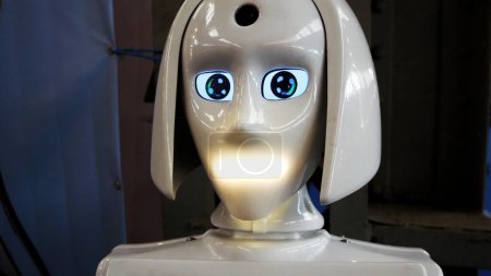 Téléchargez les photos : Le robot blanc parle, tourne la tête et tourne les yeux. Intelligence artificielle en tant qu'assistant humain, robot manager. - en image libre de droit