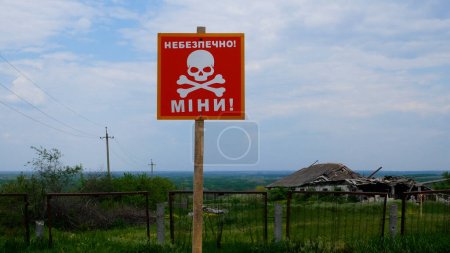 Photo for A sign that reads Caution, mines. Against the background of green grass in a Ukrainian village. Mined areas. The danger of mined areas for civilians in Ukraine. Russian-Ukrainian War 2022-2023 - Royalty Free Image