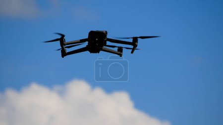 Photo for The drone flies in the sky against the background of clouds. The propellers are spinning. The drone is hovering in the sky and conducting surveillance and filming - Royalty Free Image