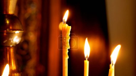 Photo for Candles burning in the church in the dark on the background of a cross. Church service. Church sacraments, prayer. Wax dripping down a burning candle - Royalty Free Image