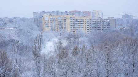 Eine Metropole im Schnee. Im Hintergrund schneebedeckte Bäume und mehrstöckige Gebäude. Ansicht von oben. Szene eines verschneiten Winters in einer Großstadt.