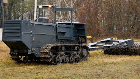 Foto de Un vehículo de desminado con un eje de metal pesado atraviesa un campo con minas. Desminado humanitario de campos. - Imagen libre de derechos