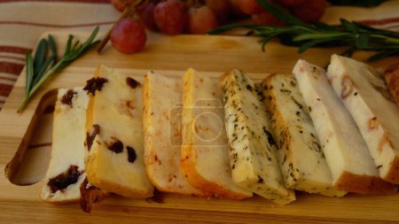 Different types of hard cheeses with additives on a wooden board on the table. Panorama. Cheeses in the gourmets diet.