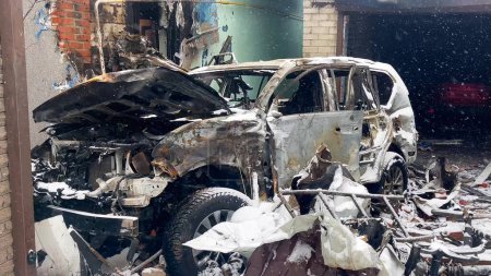 Ein ausgebranntes und verstümmeltes Auto nach einem Raketeneinschlag im Hof eines Wohnhauses. Russisch-ukrainischer Krieg.