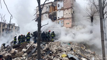 Foto de Kharkiv, Ucrania - 23 de enero de 2024: Escombros de un edificio residencial destruido por un ataque con misiles en una ciudad ucraniana. Una operación de rescate está en marcha. Los rescatistas están desmantelando las ruinas. Humo. - Imagen libre de derechos
