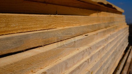 De nombreuses planches de bois se trouvent au sol en plein air. Matériaux de construction pour la construction de la future maison.