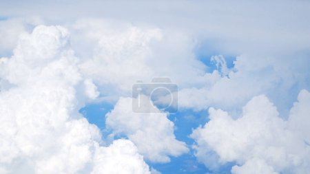 The camera floats over white clouds against a blue sky. View from above. Panorama.