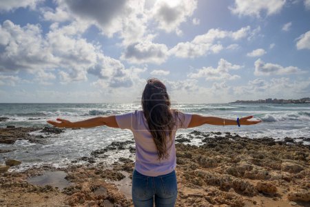 Téléchargez les photos : Femme heureuse célébrant ses vacances devant la mer Méditerranée dans un paysage côtier. - en image libre de droit
