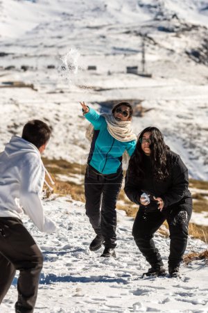 Téléchargez les photos : Famille latine à la station de ski, à granada sierra nevada s'amuser à lancer des boules de neige, jouer sur une journée ensoleillée, andalucia, espagne, - en image libre de droit