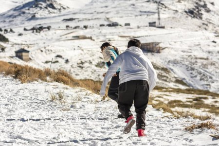 Téléchargez les photos : Mère latine et fils qui courent dans la neige à Sierra Nevada Grenade, Andalousie Espagne - en image libre de droit