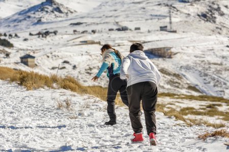 Téléchargez les photos : Garçons latins courant dans la neige par une journée ensoleillée dans les montagnes - en image libre de droit
