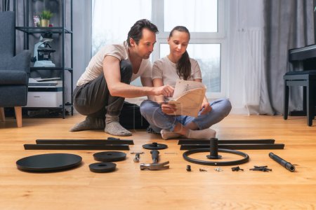 Husband and wife are looking through the instructions for self-assembly of furniture at home together.  Family time together, mutual help and male support in difficult everyday situations.