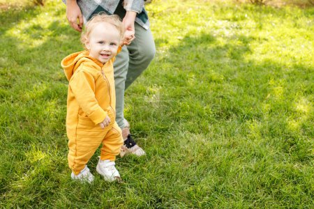 Téléchargez les photos : Baby with mom takes the first steps in the park. child development - en image libre de droit