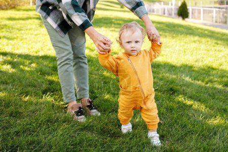 Téléchargez les photos : Baby with mom makes first steps in the park - en image libre de droit