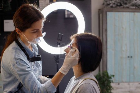 Foto de Beautician combing eyebrows to woman in salon - Imagen libre de derechos