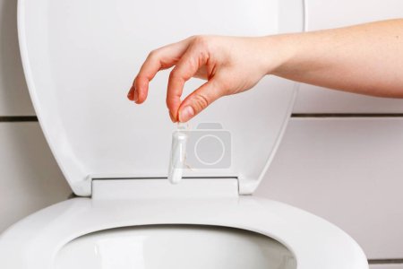 Téléchargez les photos : Jeter un tampon dans les toilettes - Gros plan - en image libre de droit