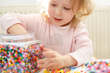 Nahaufnahme eines 3-jährigen Mädchens, das Hama-Perlen spielt