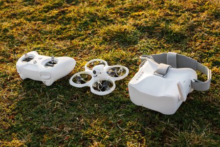 Ein kompletter Drohnen-Bausatz mit Fernbedienung, Brille und Quadcopter auf sattgrünem Gras