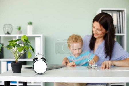 Photo for Clock mockup against background of working woman with a child - Royalty Free Image
