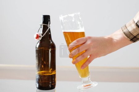 Foto de Un vaso de cerveza en la mano de una mujer. cerveza. mujer sosteniendo cerveza en la mano - Imagen libre de derechos