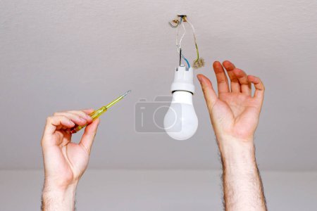 close-up of a man unscrewing a light bulb