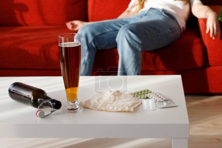 Téléchargez les photos : Drogues alcoolisées sur la table à la maison mauvaises habitudes. femme en arrière-plan - en image libre de droit