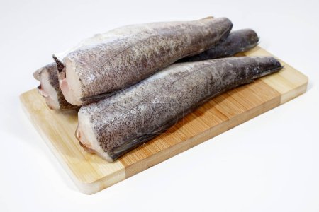 Téléchargez les photos : Poisson de merlu frais prêt à cuire sur une planche de cuisine en bois - en image libre de droit