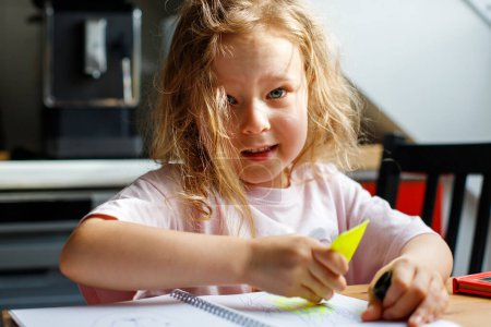 4-s Mädchen zeichnet zu Hause in der Küche. Kinderentwicklung, Kindergarten, Soziales und Familie