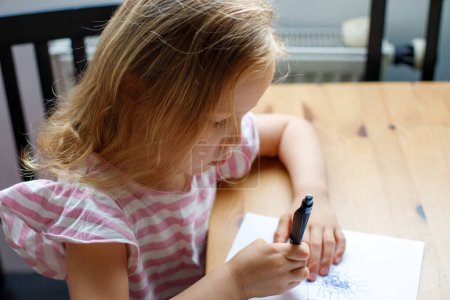 Mädchen zeichnet zu Hause in der Küche. Kinderentwicklung, Kindergarten, Soziales und Familie