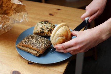 A close-up of a woman cutting various breakfast bread rolls. German breakfast buns
