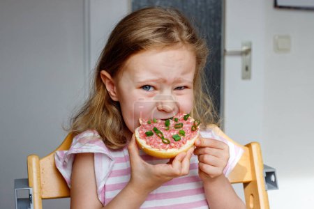 Mettbrotchen. Mädchen isst ein Brötchen mit roh eingelegtem Hackfleisch. Traditionelles deutsches Frühstück.