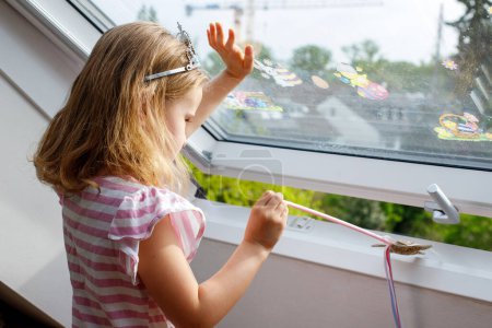 una chica intenta abrir una ventana en casa. peligro para los niños
