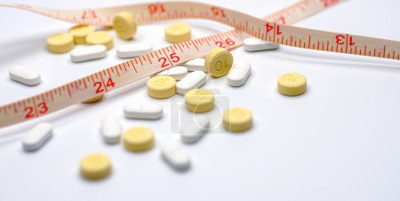 Téléchargez les photos : Mesurer la bande et les pilules pour le concept de régime. soins médicaux et prévention. Diet pills et ruban à mesurer. - en image libre de droit