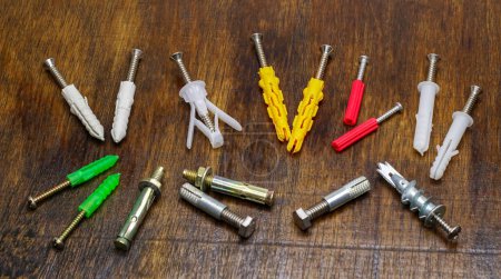 Wall plugs, also known as screw anchors or dowels, in different colors and sizes, on wood background